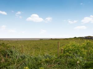 a field of grass with a fence in the foreground at Eastcliff Bungalow in Mundesley