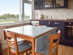 a kitchen with blue cabinets and a table and chairs at Eastcliff Bungalow in Mundesley