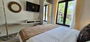 a bedroom with a bed and a tv and a window at Cozy 1Bedroom House with Kitchen Work Space in Nusa Dua