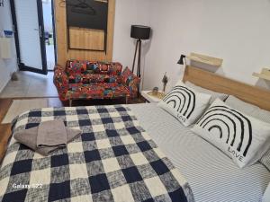 a bedroom with a bed with a blanket and a chair at Georgia Tiny House - Hiperbara Livezeni Mures in Livezeni