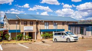a white van parked in a parking lot in front of a building at Scenery Guesthouse Stadium in Maseru