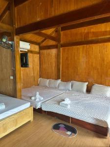 two beds in a room with wooden walls at Nhà trên đồi - Windy Hill in Mù Cang Chải +6 photos