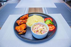 a plate of food with chicken and rice on a table at Scenery Guesthouse Stadium in Maseru +10 photos