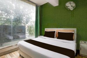 a bedroom with a large bed with a green wall at Hotel O Square Residency in Rājpur