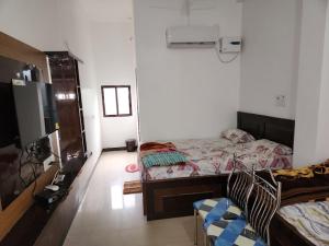 a bedroom with two beds and a television in it at Om Hotel & Lodge in Baharāgora