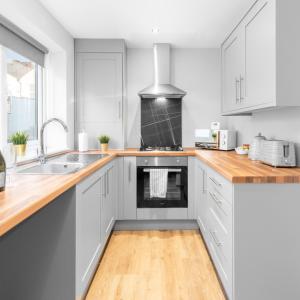 a kitchen with white cabinets and wooden counter tops at Modern 2 Bed Apartment - 2 Parking Spaces - Sleeps 3 - Netflix 1BS in Amblecote