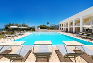 a swimming pool with tables and chairs in front of a building at Residence Solaris in San Foca