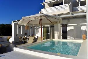a swimming pool with an umbrella on a house at Etereo Suite in Adamantas