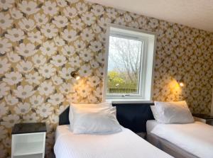 a room with two beds and a window with flowers at The Weigh Inn Hotel & Lodges in Thurso +42 photos