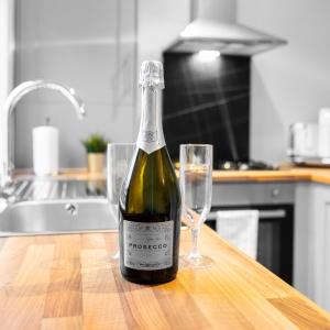 a bottle of wine sitting on a table with a glass at Modern 2 Bed Apartment - 2 Parking Spaces - Sleeps 3 - Netflix 1BS in Amblecote