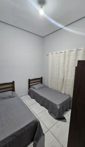 a bedroom with two beds and a window at Casa próxima à Praia do Cerrado e centro in Goianésia
