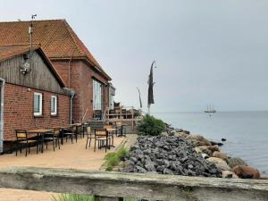 a building with tables and chairs next to the water at Möwenhorst in Fehmarn