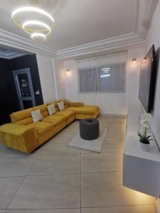 a living room with a yellow couch and a table at Studio VIP - Bonamoussadi - Groupe électrogène - 2douches in Douala