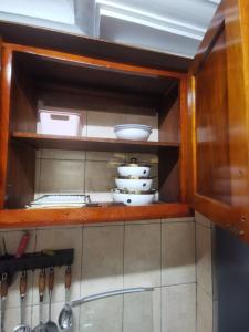 a kitchen cabinet with dishes and utensils in it at Studio VIP - Bonamoussadi - Groupe électrogène - 2douches in Douala +44 photos