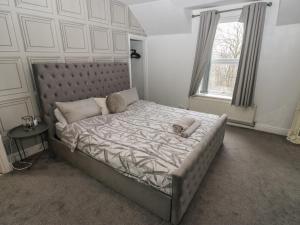 a bedroom with a bed with a headboard and a window at Chestnut Lodge in Bradford