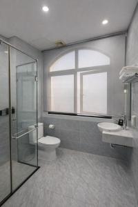 a bathroom with a toilet and a sink and a window at Tom Tom Homestay in Phú Quốc