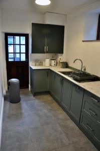 a kitchen with green cabinets and a sink at Ash Cottage - Caerleon in Newport