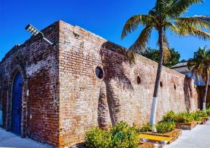 a brick building with a palm tree behind it at Grand Hotel Excelsior Port Royal in Kingston