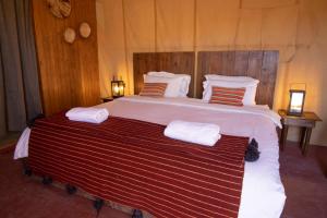 a large bed with two towels on top of it at Erg chegaga Daya Luxury Camp - Sahara Desert Stay in Mhamid