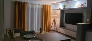 a dining room with a table and a television at La chambre des tentations , love room avec jacuzzi in Bages +7 photos