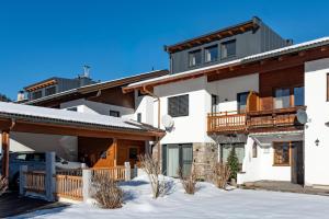 a house in the snow with a car parked in front at Appart Christophorus in Söll