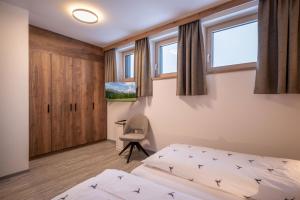 a bedroom with a bed and a desk and windows at Appart Christophorus in Söll