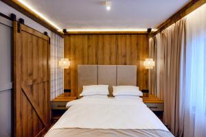 a bedroom with a bed and a wooden wall at Celeste Luxury Apartments in Ranca