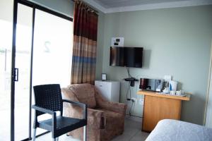 a living room with a couch and a chair and a tv at Bernliz Guest House in Bokong