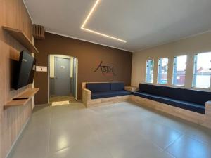 a waiting room with a blue couch and a tv at Astor Suítes - Unicamp in Campinas