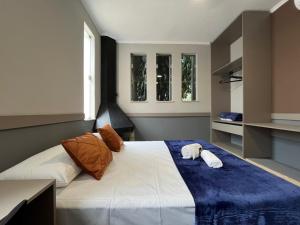 a bedroom with a large bed with two pillows on it at Astor Suítes - Unicamp in Campinas