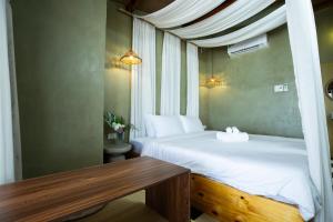 a bedroom with two beds and a wooden table at Ruby's Home- Doc Let's House in Ngân Hà