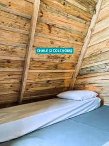 a bed in a wooden room with a sign on the ceiling at Hostel Costa Terral in Matinhos