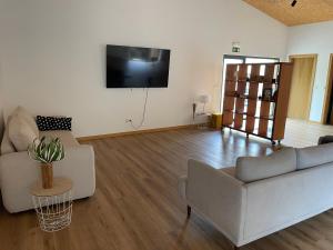 a living room with a couch and a tv on the wall at Quinta Casal de Bordeiro in Góis