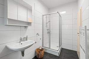 a white bathroom with a sink and a shower at Mivano Apartments - Allergarten in Celle