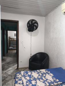 a bedroom with a bed and a black chair at Sobrado há 7 quadras da praia in Matinhos