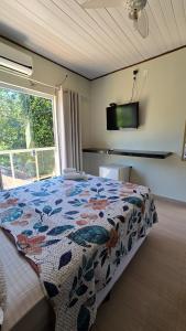 a bedroom with a bed with a flowered blanket and a window at Pousada Colibri in Trindade