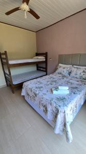 a bedroom with a large bed with a fan and a bed sidx sidx sidx at Pousada Colibri in Trindade