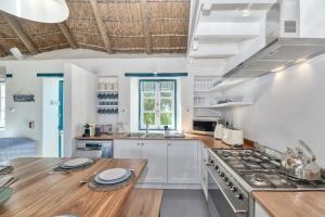 a kitchen with white cabinets and a wooden counter top at Cape Creek Cottage, Luxury Coastal Getaway in Struisbaai