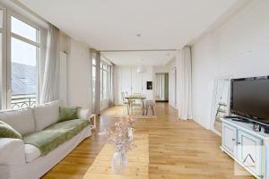 a living room with a couch and a tv at Le Palais du Commerce in Rennes