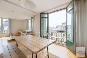 a living room with a wooden table and a balcony at Le Palais du Commerce in Rennes
