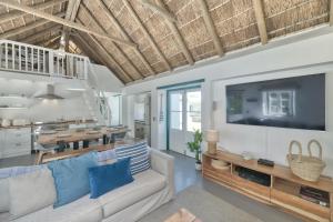 a living room with a couch and a tv at Cape Creek Cottage, Luxury Coastal Getaway in Struisbaai