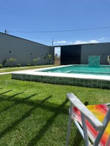Ein Stuhl steht im Gras neben einem Swimmingpool. in der Unterkunft DeckMC in Itarema