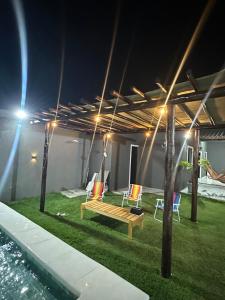eine Terrasse mit Bank und Stühlen auf dem Rasen in der Unterkunft DeckMC in Itarema