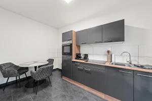 a kitchen with black cabinets and a table with chairs at Mivano Apartments - Allergarten in Celle