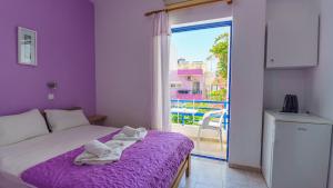 a bedroom with a bed with purple sheets and a window at Blue Sky in Palaiochora