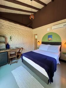 a bedroom with a large bed and a desk at Hostel Antônio Pescador - Centro da Guarda do Embaú in Guarda do Embaú