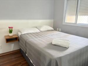 a bedroom with a bed with a white blanket and a window at 1506 - studio novo e completo in Guarulhos +28 photos