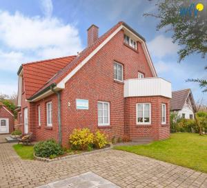 a red brick house with a grass yard at Godenhus Ferienwohnung Mathis in Langeoog