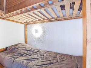 a bed in a room with a white wall at Studio Les Olympiades-28 by Interhome in Val Thorens