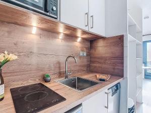 a kitchen with a sink and a wooden wall at Studio Les Olympiades-28 by Interhome in Val Thorens